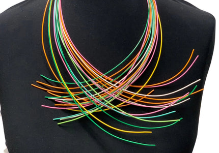 A multi-colored necklace displayed on a mannequin, featuring numerous slender wires in various colors arranged in a layered pattern.