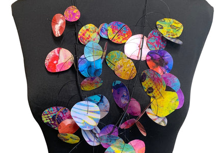 A multi-colored necklace with circular pendants displayed on a mannequin torso.