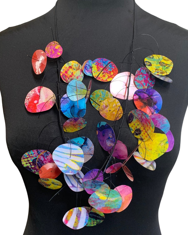 A multi-colored necklace with circular pendants displayed on a mannequin torso.