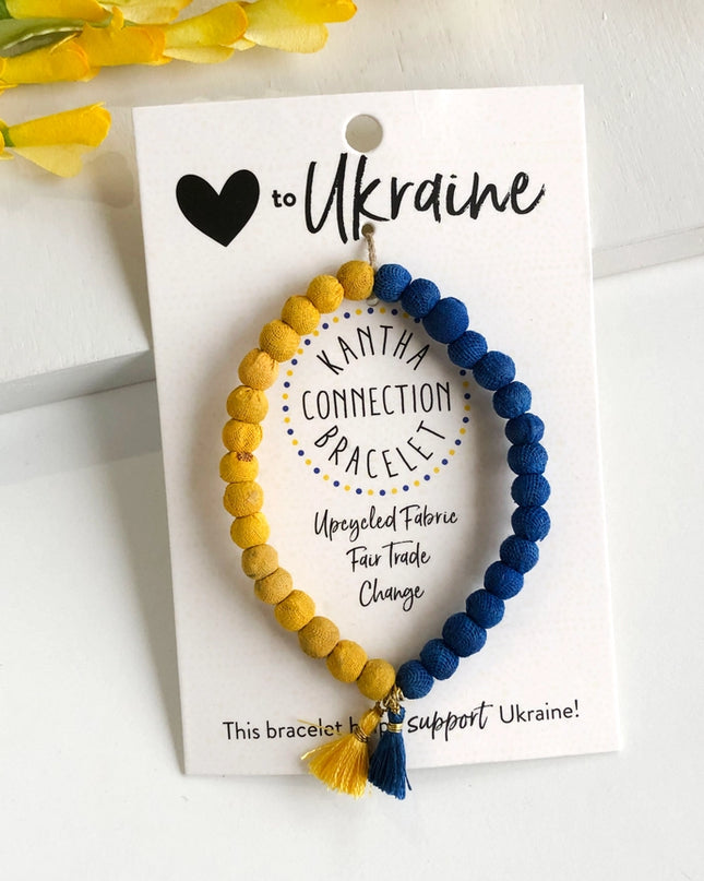 A bracelet with blue and yellow beads, and a tassel, displayed on a card with text supporting Ukraine.