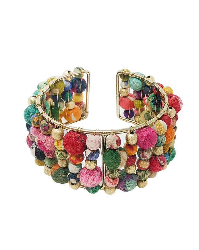A colorful beaded cuff bracelet made from layers of Kantha beads with gold accents, displayed against a white background.