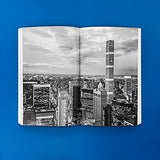 Open book showing full page black and white cityscapes on a blue background